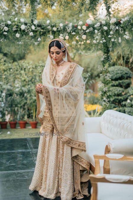 Photo of Bride wearing a white and gold sharara set on her wedding day.