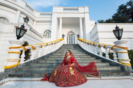 Photo of Bridal portrait on stairs with bride in red bridal lehenga