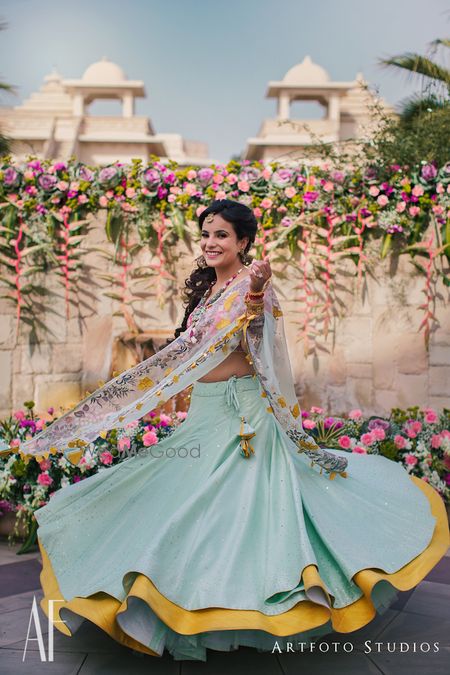 Photo of Bride twirling in mustard and blue mehendi lehenga