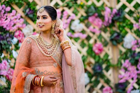 Photo of bride in peach bridal lehenga and unique necklace