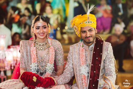 Photo of matching bride and groom with a contrasting yellow safa