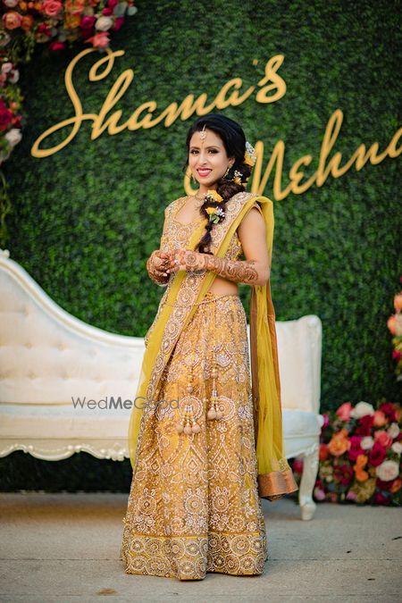 Photo of Bridal mehendi look in mustard lehenga and side braid with flowers