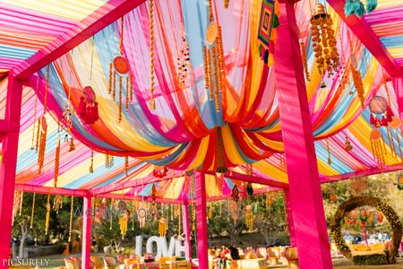 Photo of Colourful mehendi decor idea with drapes and elements