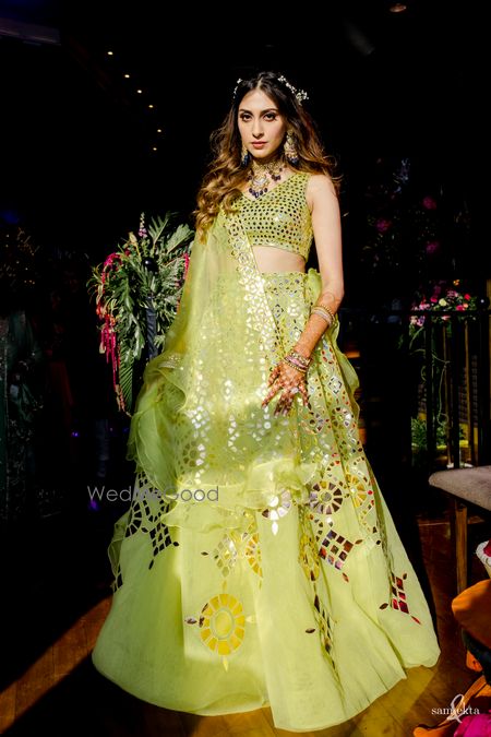 Photo of bride in lime green lehenga on her mehendi with open wavy hair