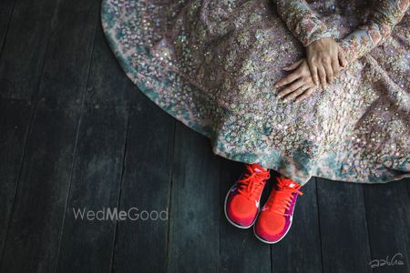 Photo of Bride wearing red sneakers under bridal lehenga