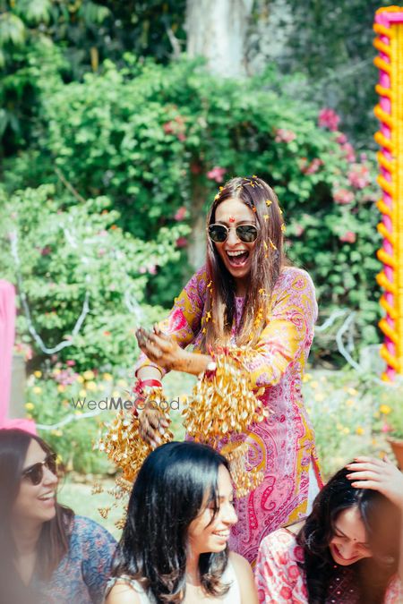 Photo of Bride dropping golden kaleere on bridesmaid