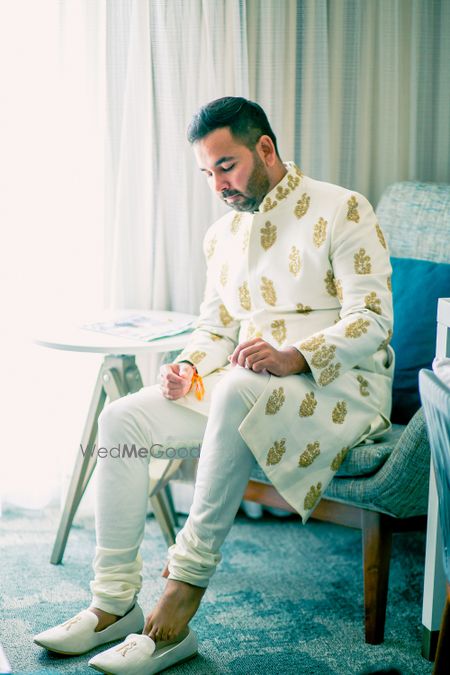 Photo of Groom in gold and white sherwani with buti design