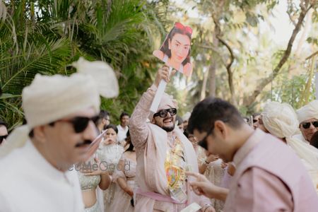 Photo of Super fun groom entry with bride's photos as a prop for the baraat