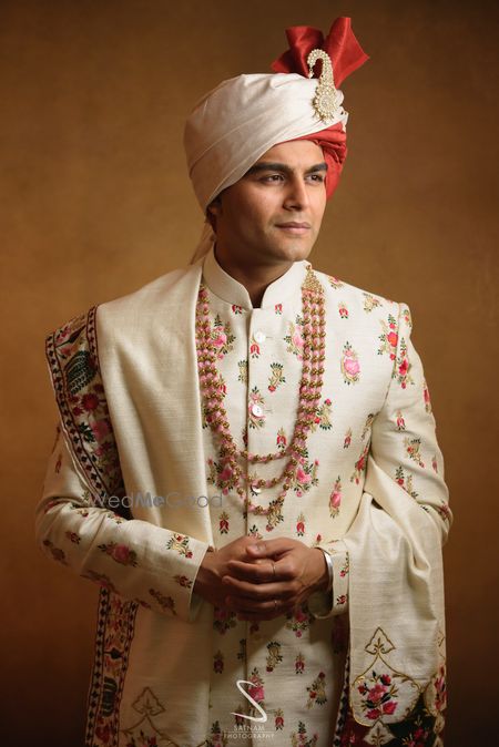 Photo of groom in a white floral sherwani and safa