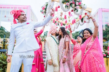 Photo of happy couple kissing under phoolon ki chadar with family