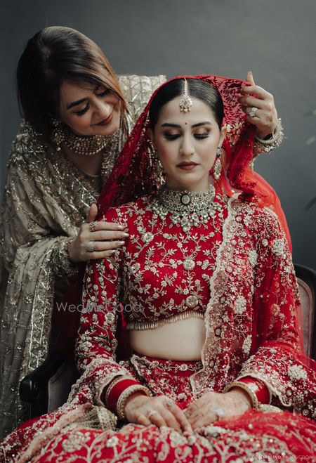 Photo of Lovely capture of the mother of the bride placing the veil dupatta on the bride's head on the wedding day