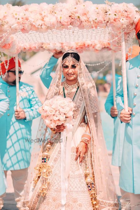 Photo of Bride under peach phoolon ka chadar with bouquet