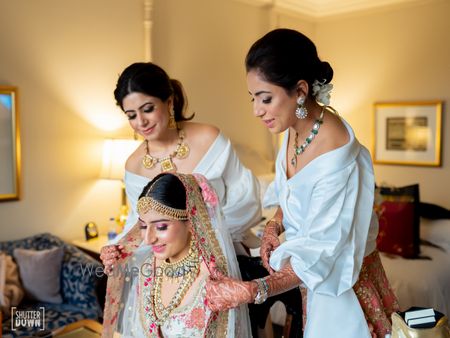 Photo of Bridesmaids helping bride get ready