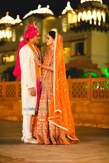 Photo of A newly wedded bride and groom pose in coordinated outfits