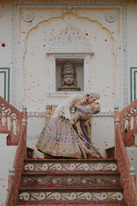 Photo of Super adorable shot of the couple kissing under a floral shower after just getting married