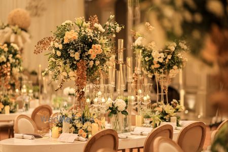 Photo of Gorgeous white and green floral centrepieces with glass and candle detailing for wedding table set-up