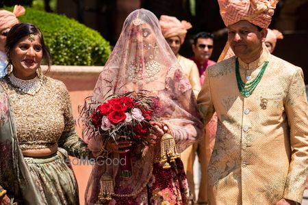 Photo of bridal entry with her parents holding a maroon bouquet