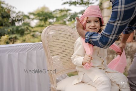 Photo of Cute capture of a kid tying a safa at the wedding