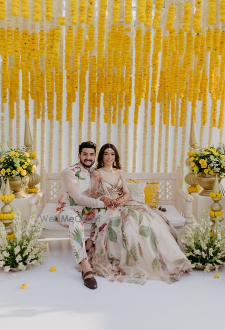 Photo of Beautiful couple portrait in co-ordinated floral outfits with yellow gendaphool decor