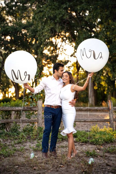 Photo of pre wedding shoot idea with bride and groom holding mr and mrs props