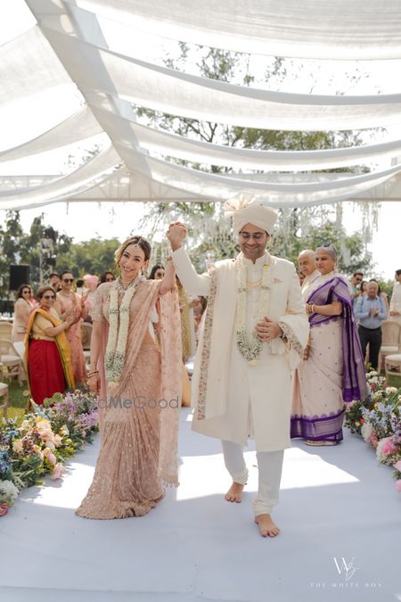 Photo of Just married shot of the couple with white jaimalas and pastel outfits