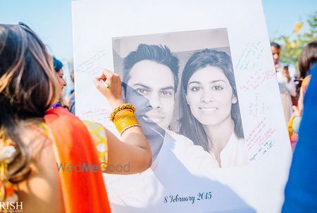 Photo of Guests sign and leave messages on a guest book which is a printed photo of the bride and groom