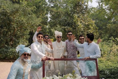 Photo of The groom entering the baraat in a vintage car with all his groomsmen