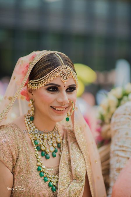 Photo of Pretty bridal portrait in peach lehenga and green jewellery