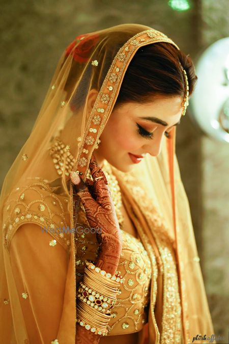 Photo of Bridal portrait in orange lehenga and contrasting bun