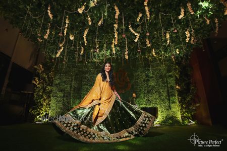 Photo of bride twirling in a green velvet lehenga