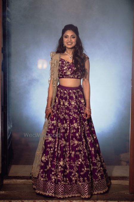 Photo of Bride wearing an aubergine lehenga with a scalloped dupatta.