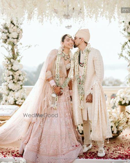 Photo of Pretty shot of the groom kissing the bride as they just got married in a pastel theme wedding