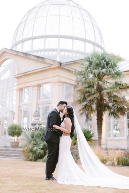 Photo of bride in white grown and groom in tuxedo pose on wedding day