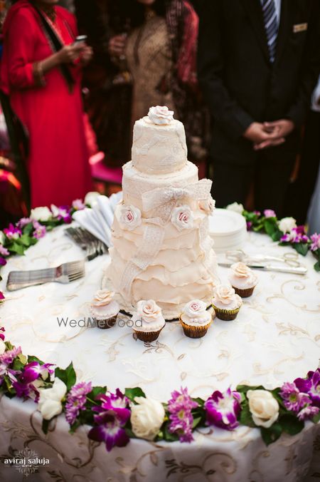 Photo of White wedding cake with cupcakes