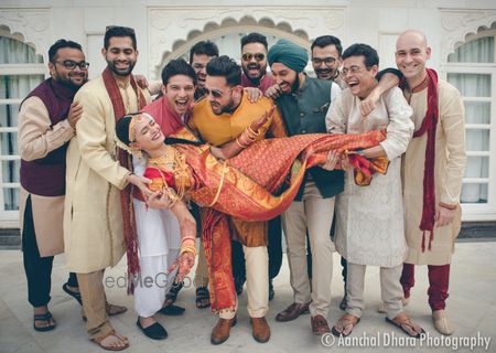 Photo of Fun bridal portrait with groomsmen picking bride up