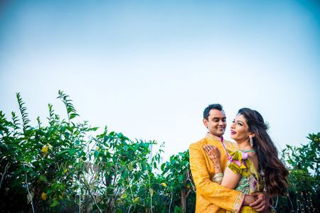 Photo of A bride and groom to be in yellow pose at their mehendi ceremony