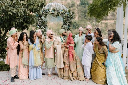 Photo of Fun family portrait with the couple kissing on their wedding day