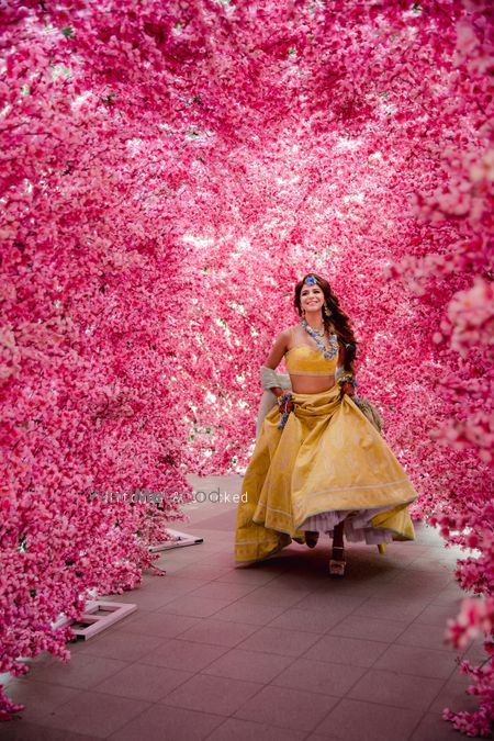 Photo of A bride in a yellow lehenga for her mehndi with floral jewellery