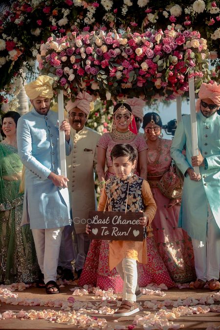 Photo of Bride entering with her brother and a kid holding a placard