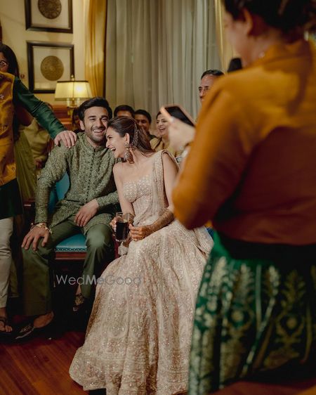 Photo of Happy couple portrait for a mehendi event with bride in a strapless gown saree and groom in an olive green short sherwani