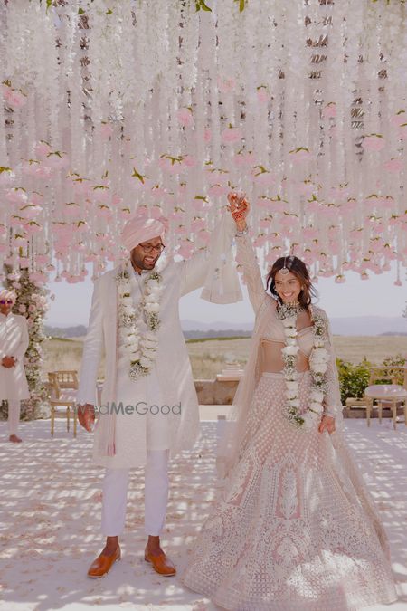 Photo of Happy just-married couple portrait with mandap decor in white and pink