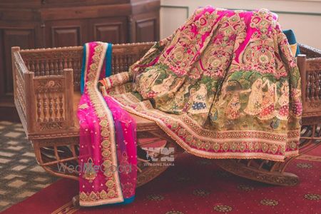 Photo of bright pink bridal lehenga in raw silk with green border with unique dancing girls motifs from ancient india