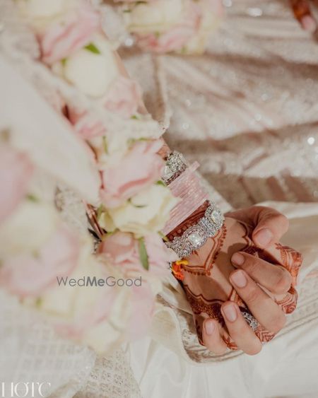 Photo of Pretty shot of the couple holding hands with baby pink chooda and minimal mehendi details