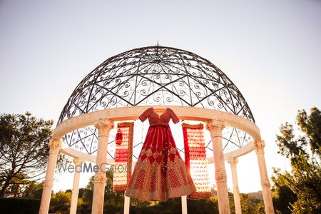 Photo of Red coloured sabyasachi bridal lehenga on hanger over dome