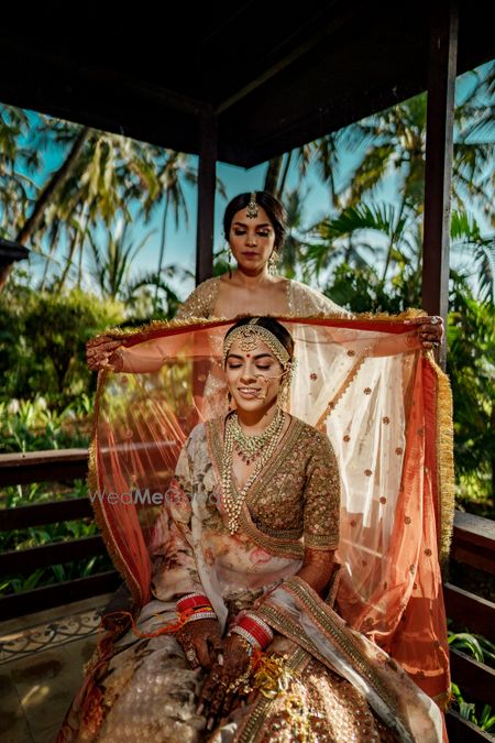 Photo of bridesmaid placing dupatta on brides head shot