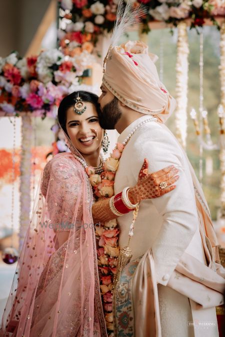 Photo of Beautiful shot of groom kissing on bride's forehead.