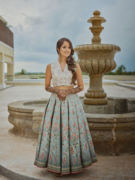 Photo of bride wearing a short lehenga with side braid for her mehendi