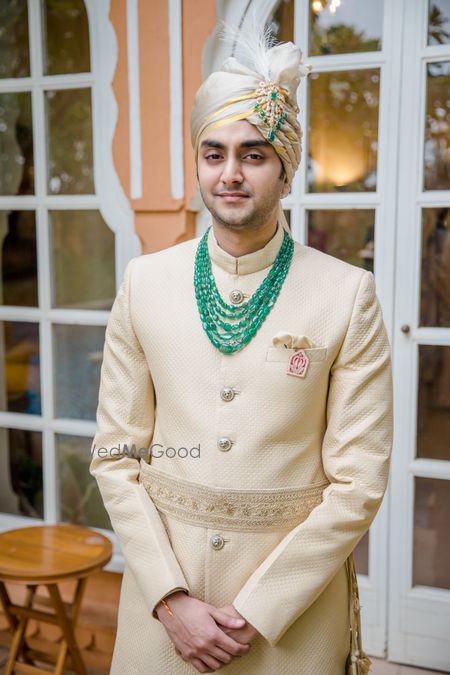 Photo of Groom wearing an off-white sherwani with a layered necklace.