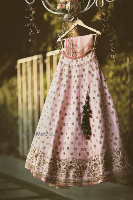 Photo of Light pink and gold lehenga with black tassels on hanger