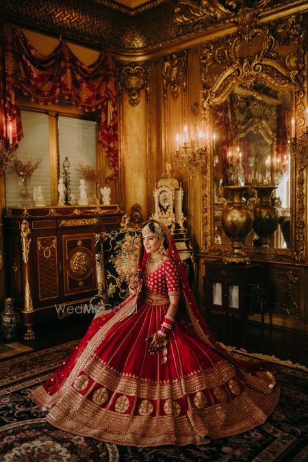 Photo of bride wearing a red and gold sabya lehenga with regal vibes